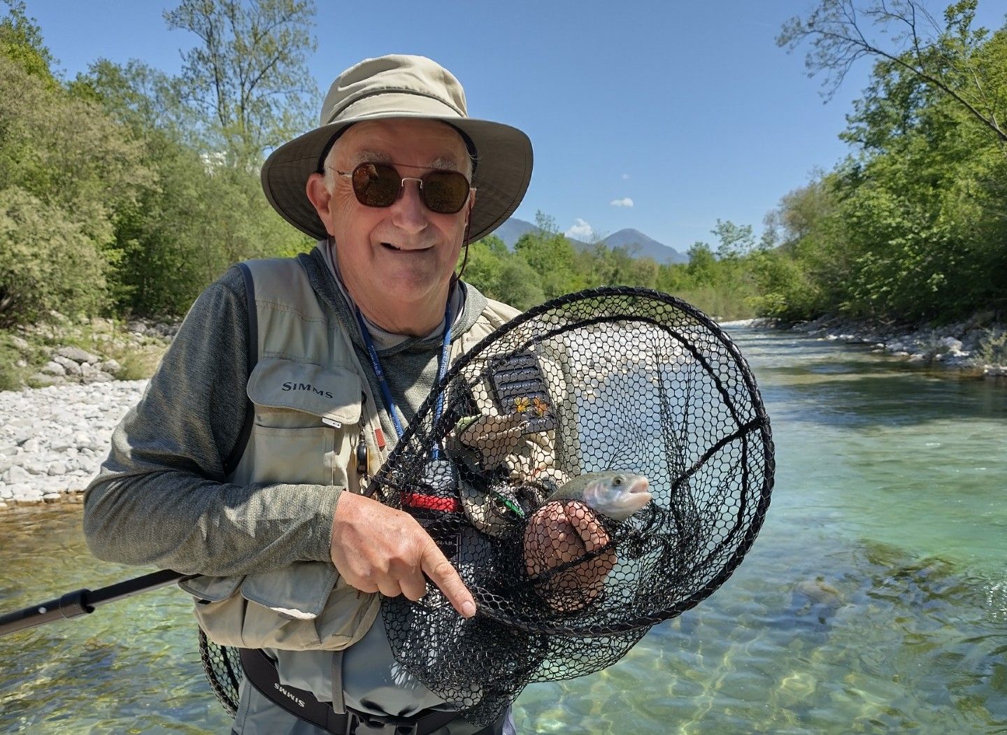 Dirk Lub holding a caught fish in net in front of a river