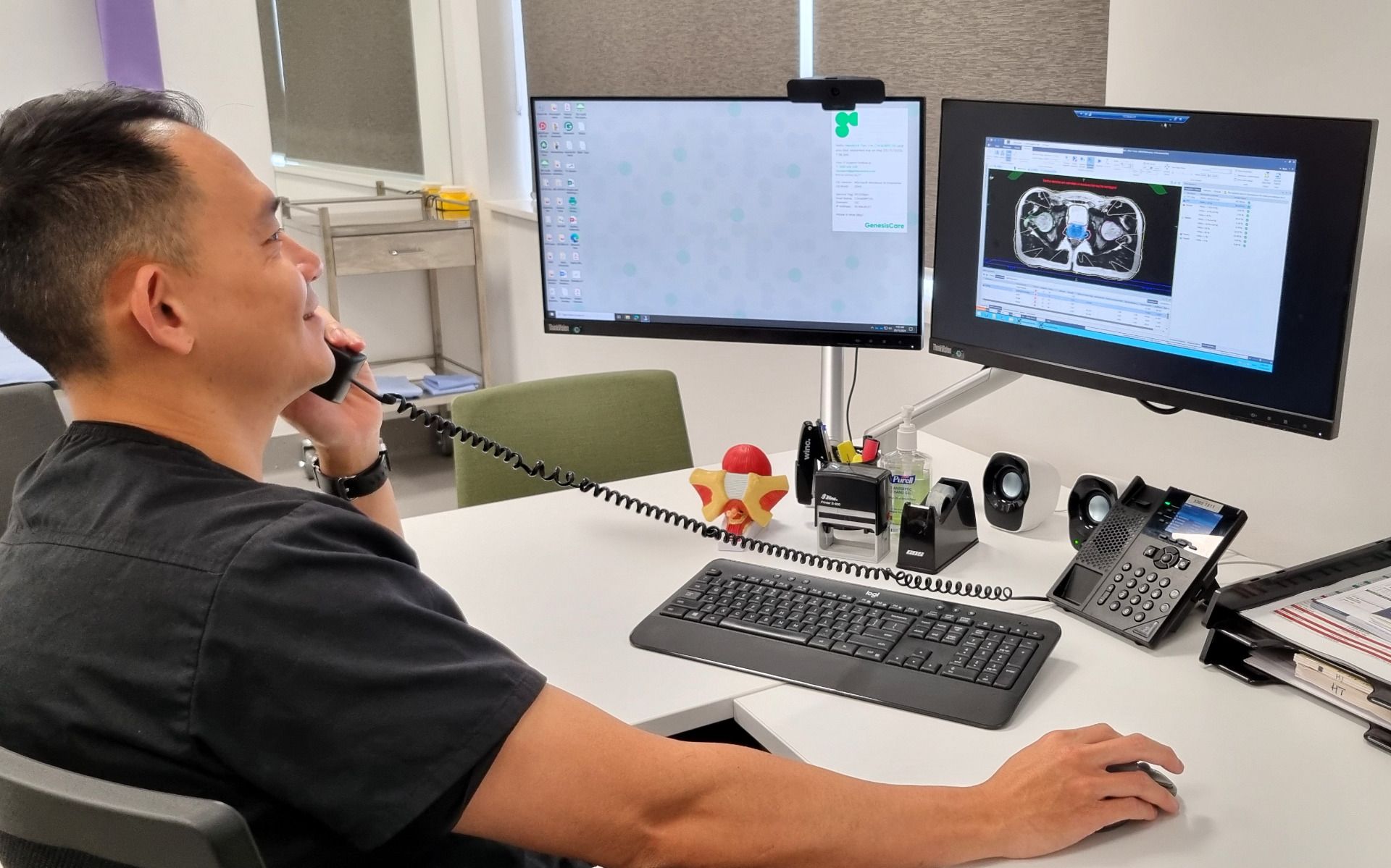 Dr Tan working at his computer, while talking on the phone