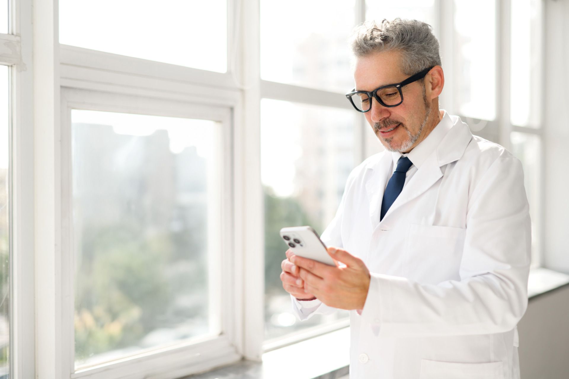 Man Wearing a White Coat Looking at His Phone